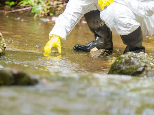 Image of a Person collecting water sample (Hydrology) Photo